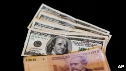 FILE - U.S. dollar bills and Argentine pesos are displayed for the photographer on a table at a currency exchange business in Buenos Aires, Argentina, Jan. 23, 2014.