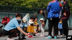Residents bring their children to play in a compound near a commercial office building in Beijing on May 10, 2021. (AP Photo/Andy Wong)