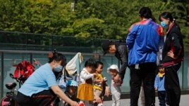Residents bring their children to play in a compound near a commercial office building in Beijing on May 10, 2021. (AP Photo/Andy Wong)