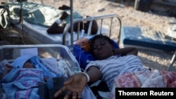 Una mujer en una camilla es fotografiada junto a un bebé después del terremoto de magnitud 7,2 en Les Cayes.