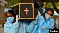Volunteers carry the body of a person who died from the coronavirus disease (COVID-19) for burial at a cemetery in Bengaluru, India, May 18, 2021. 