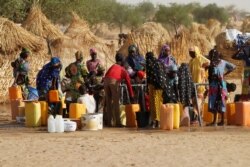 FILE - Women collect water at the Boudouri site for displaced persons outside the town of Diffa in southeastern Niger, June 21, 2016.