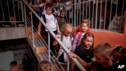 FILE - Children from Gymnasium No. 6 head to a basement set up with classrooms during an air alert in Zaporizhzhia, Ukraine, Sept. 3, 2024. 