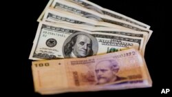 FILE - U.S. dollar bills and Argentine pesos are displayed for the photographer on a table at a currency exchange business in Buenos Aires, Argentina, Jan. 23, 2014.