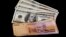 FILE - U.S. dollar bills and Argentine pesos are displayed for the photographer on a table at a currency exchange business in Buenos Aires, Argentina, Jan. 23, 2014.