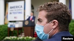 A Trump administration staffer wears a protective face mask in the Rose Garden as U.S. President Donald Trump holds a coronavirus disease (COVID-19) outbreak response briefing at the White House in Washington, May 11, 2020.