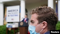 A Trump administration staffer wears a protective face mask in the Rose Garden as U.S. President Donald Trump holds a coronavirus disease (COVID-19) outbreak response briefing at the White House in Washington, May 11, 2020.