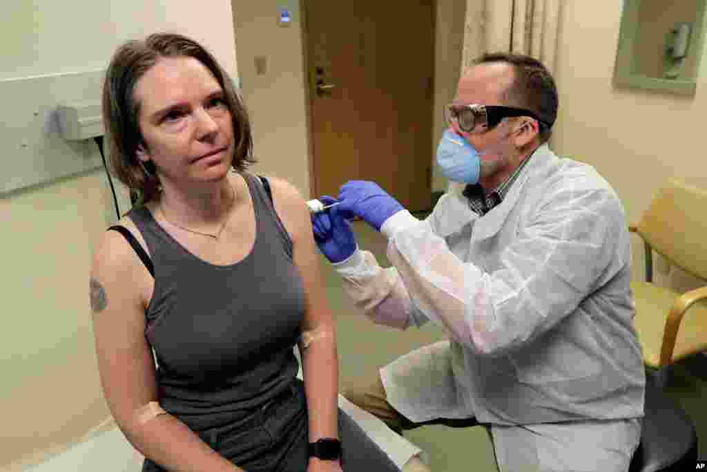 A pharmacist gives Jennifer Haller, left, the first shot in the first-stage safety study clinical trial of a potential vaccine for COVID-19 at the Kaiser Permanente Washington Health Research Institute in Seattle.