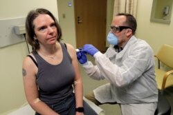 A pharmacist gives Jennifer Haller, left, the first shot in the first-stage safety study clinical trial of a potential vaccine for COVID-19 at the Kaiser Permanente Washington Health Research Institute in Seattle, Washington, March 16, 2020.