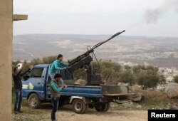 FILE - A rebel fighter from the Ahrar al-Sham Islamic Movement fires an anti-aircraft weapon towards what they said was a helicopter belonging to forces loyal to Syria's President Bashar al-Assad in Jabal al-Zawiya in the southern countryside of Idlib.