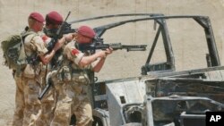 FILE - British soldiers take up position behind the wreckage of a vehicle in the village of Majar al-Kabir, Iraq, June 28, 2003. 