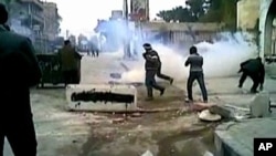 This still image taken from video off a social media website shows protesters covering their faces from tear gas being fired in a Damascus suburb, December 30, 2011.