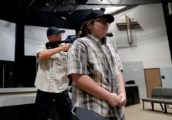 Brett Faulkner, left, fires blanks out of an assault rifle as he and Julia Gant, right, participate in a hostage-taking scenario during a security training session at Fellowship of the Parks campus in Haslet, Texas, July 21, 2019.