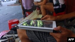 FILE - A customer uses his tablet to access the Internet at a 'wifi coffee shop' in downtown Hanoi.