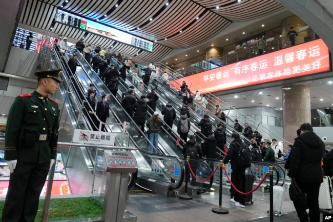 2025年1月18日,北京西站内站岗的武警士兵和准备乘坐火车回家过春节的返乡大军。
