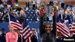 Serena Williams mengangkat piala kemenangannya setelah mengalahkan Victoria Azarenka dari Belarus (kiri) dalam final pertandingan tenis tunggal putri memperebutkan piala Amerika Terbuka di New York (8/9).