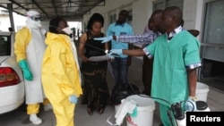 FILE - A health worker sprays a colleague with disinfectant during a training session for Congolese health workers to deal with Ebola virus in Kinshasa, Oct. 21, 2014.