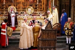 El príncipe William le pone una túnica al rey Carlos III durante su ceremonia de coronación en la Abadía de Westminster, Londres, el sábado 6 de mayo de 2023. (Yui Mok, vía AP)
