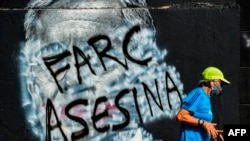 Un hombre pasa corriendo junto a un mural contra el expresidente colombiano (2002-2010) Álvaro Uribe, que fue pintado y ahora muestra un graffiti contra las FARC, una vez grupo guerrillero y ahora el partido político.