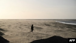 A person walks among the blows sand on St Annes beach in Lytham St Annes, near Blackpool, north-west England on Jan. 24, 2025, as storm Eowyn brings winds of 100 mph to the UK and Ireland. 