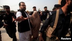 Policemen escort Sharbat Gula (in burqa), the green-eyed Afghan woman who became a symbol of her country's wars 30 years ago when her photo as a girl appeared on the cover of National Geographic magazine, as she arrives at a court in Peshawar, Pakistan, November 4, 2016.