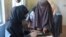 A woman voter, right, has her finger scanned before casting her vote during parliamentary elections in Kandahar, south of Afghanistan, Oct. 27, 2018.