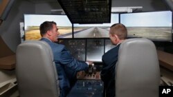 Oklahoma Gov. Kevin Stitt, left, tries his hand at a 747 flight simulator under the eye of Shawn Lynch, right, chief flight instructor, at the Oklahoma City facility of The Boeing Company, May 14, 2019, in Oklahoma City. 
