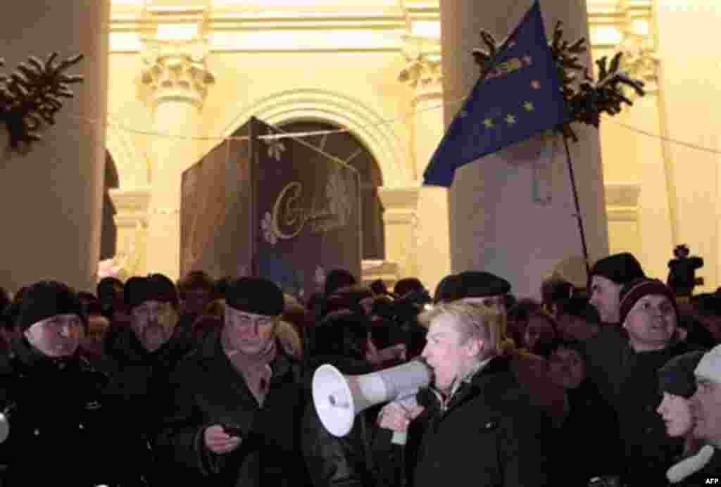 Vitaly Rymashevsky speaks through a megaphone as other opposition candidates Nikolai Statkevich, center, and Andrei Sannikov, second left, listen during during a rally in downtown Minsk, Belarus, early Monday, Dec. 20, 2010. Thousands of opposition suppor