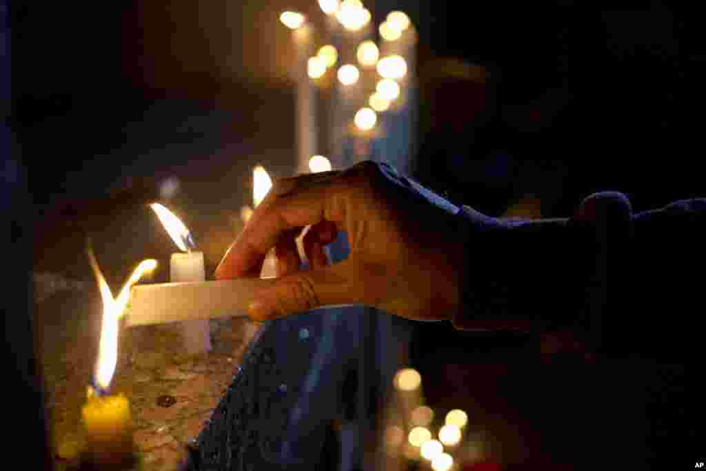 Man lights candle during vigil for victims of mass shooting at the Pulse Orlando nightclub, in front of U.S. embassy, Santiago, Chile, June 12, 2016.