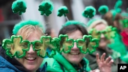 Sharon Keely, left, of Dublin, watches as participants march up Fifth Avenue during the St. Patrick's Day Parade, March 16, 2019, in New York. 