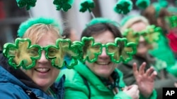 FILE - Sharon Keely, left, of Dublin, watches as participants march up Fifth Avenue during the St. Patrick's Day Parade, March 16, 2019, in New York.