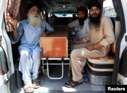 Seorang pria Sikh Afghanistan duduk di samping peti mati salah satu korban ledakan kemarin di kota Jalalabad, Afghanistan 2 Juli 2018. (Foto: Reuters)