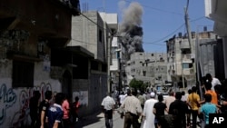 巴勒斯坦人在街上觀看以色列空襲加沙地帶後翻起的濃煙。