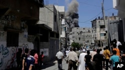 Palestinos observan el humo y el povo que se levanta tras un ataque israelí en Gaza.