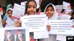 Anak-anak sekolah dasar dari Solo menunjukkan poster-poster dan foto Presiden Joko Widodo dan Wakil Presiden Ma'ruf Amin menjelang pelantikan presiden dan wapres terpilih di Solo, 19 Oktober 2019. (Foto: AFP)