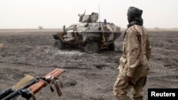 A Chadian soldier walks past an armored vehicle that the Chadian military said belonged to insurgent group Boko Haram that they destroyed in battle in Gambaru, Nigeria, Feb. 26, 2015. 