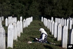 FILE - A woman is seen mourning amid tomb stones at the Potocari memorial complex near Srebrenica, Bosnia and Herzegovina, where victims of the Srebrenica massacre are buried, July 11, 2015. A genocide designation and bombing after the massacre brought the war to an end, one academic says.