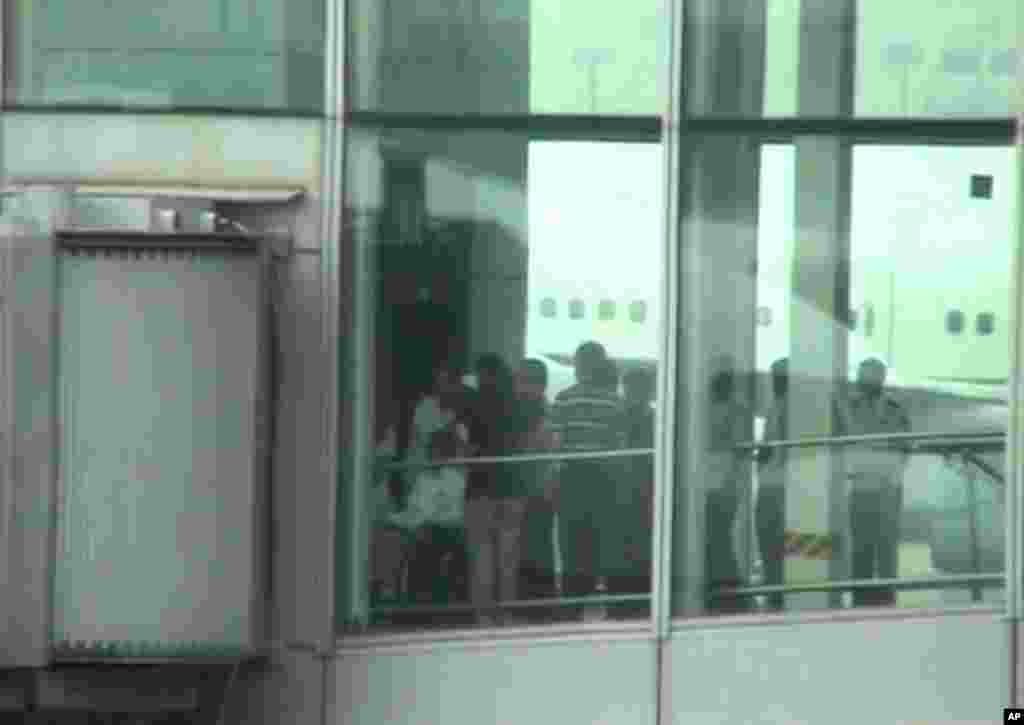 Chinese activist Chen Guangcheng, left, is pushed in a wheelchair at Beijing International airport Saturday May 19, 2012.