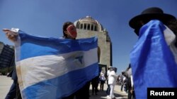 Nicaragüenses sostienen la bandera del país mientras protestan en Ciudad de México por las elecciones presidenciales en Nicaragua, el 7 de noviembre de 2021.