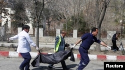 21일 아프가니스탄의 수도 카불에서 아프간 관리들이 자살폭탄 공격으로 숨진 희생자를 옮기고 있다. 