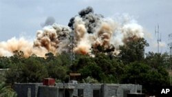 Smoke billows behind the trees following an air raid on the area of Tajura, 30 km east of Tripoli, when NATO unleashed its heaviest blitz yet of the area in a bid to speed up the ouster of Libyan leader Moammer Gadhafi, May 24, 2011