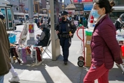 Joanna Derkacz, seorang polisi dari Kepolisian Kota New York, mengamati para pejalan kaki di Main Street, Flushing, kawasan Queens, di New York, Selasa, 30 Maret 2021. (Foto: Kathy Willens/Associated Press)