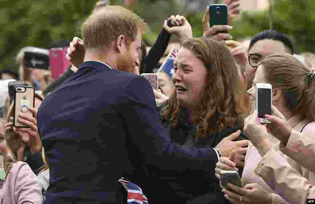 Pangeran Inggris Harry memeluk seorang penggemarnya, India Brown, saat berjalan-jalan di kota Melbourne, dalam kunjungannya di Australia.