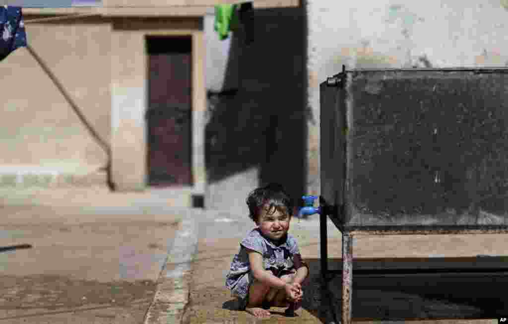 A Syrian child, whose displaced with her family due to fighting between the rebels and government forces, drinks water from a tanker in a school on the outskirts of Aleppo, Syria, September 10, 2012. 