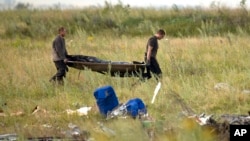 Nhân viên Bộ tình huống khẩn cấp Ukraine khiêng thi thể nạn nhân tại hiện trường vụ rơi máy bay Malaysia gần làng Hrabove, miền đông Ukraine, ngày 19/7/2014.