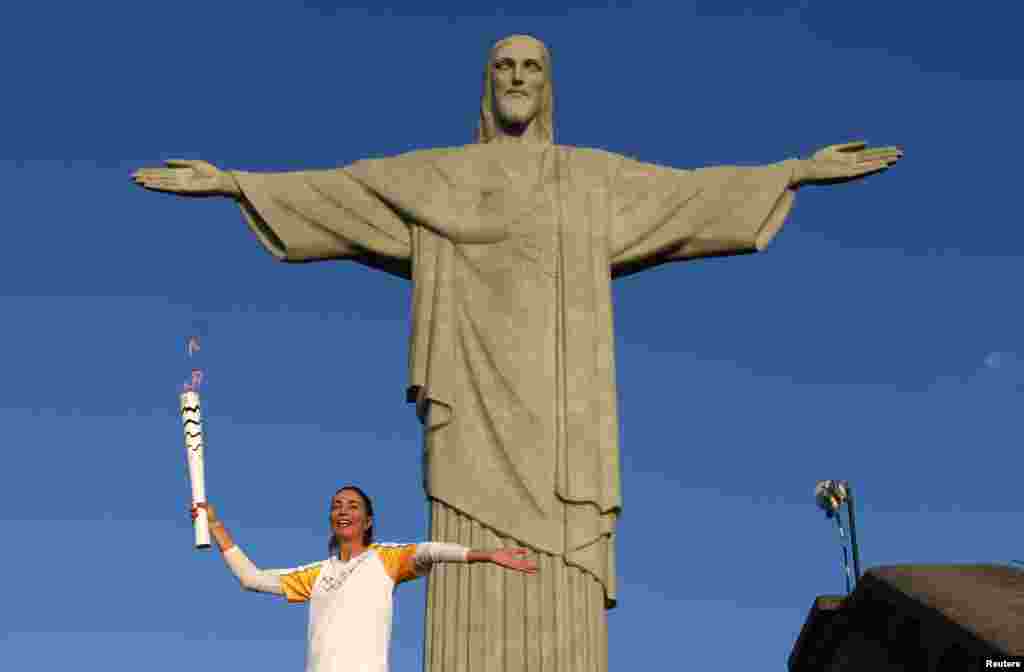 Former Brazilian volleyball player Isabel Barroso holds the Olympic torch next to Christ the Redeemer statue in Rio de Janeiro, Brazil.