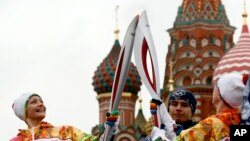 Russian Olympic gold medalists, synchronized swimmer Anastasya Davydova (L) and former artistic gymnast Svetlana Khorkina (R), join their torches during a relay of the Olympic flame in Moscow, Oct. 7, 2013. 