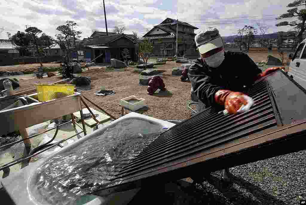 In this photo taken February 20, 2012, a man washes a door in a bathtub, in an attempt to remove radioactive contamination, outside Japan&#39;s nuclear exclusion zone.