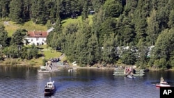 A picture taken from a farm on the coast of Hole shows survivors of the July 22 attacks in Norway gathering on Utoeya island during a visit on August 20, 2011