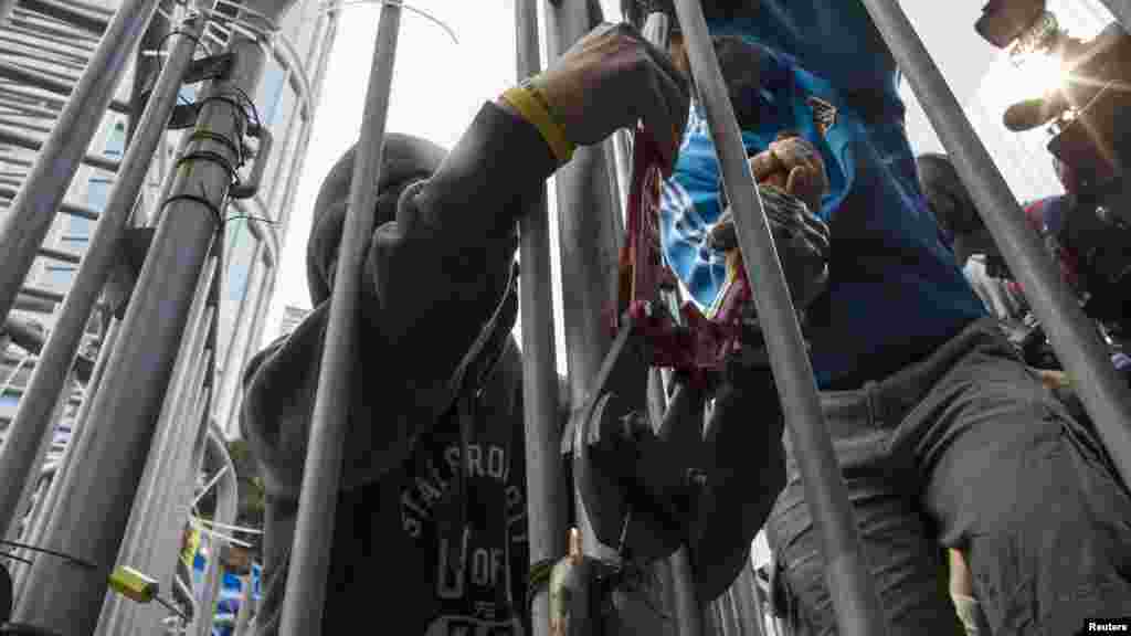 Pro-democracy protesters cut through a cable tie while dismantling a barricade outside Citic Tower in accordance with a court injunction to clear up part of the protest site outside the government headquarters in Hong Kong, Nov. 18, 2014. 